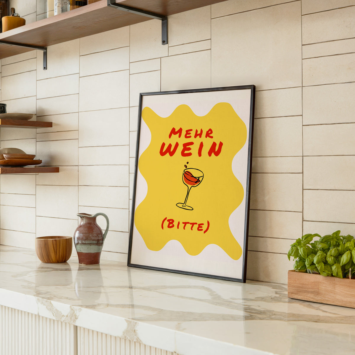 Mehr Wein Bitte print in a black frame leaning on a marble counter in a tiled kitchen