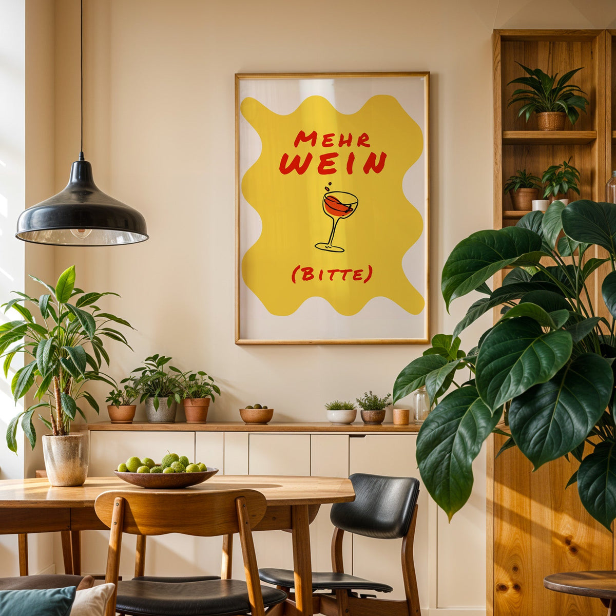 Mehr Wein Bitte print in an oak frame in a dining room above a plant-lined sideboard