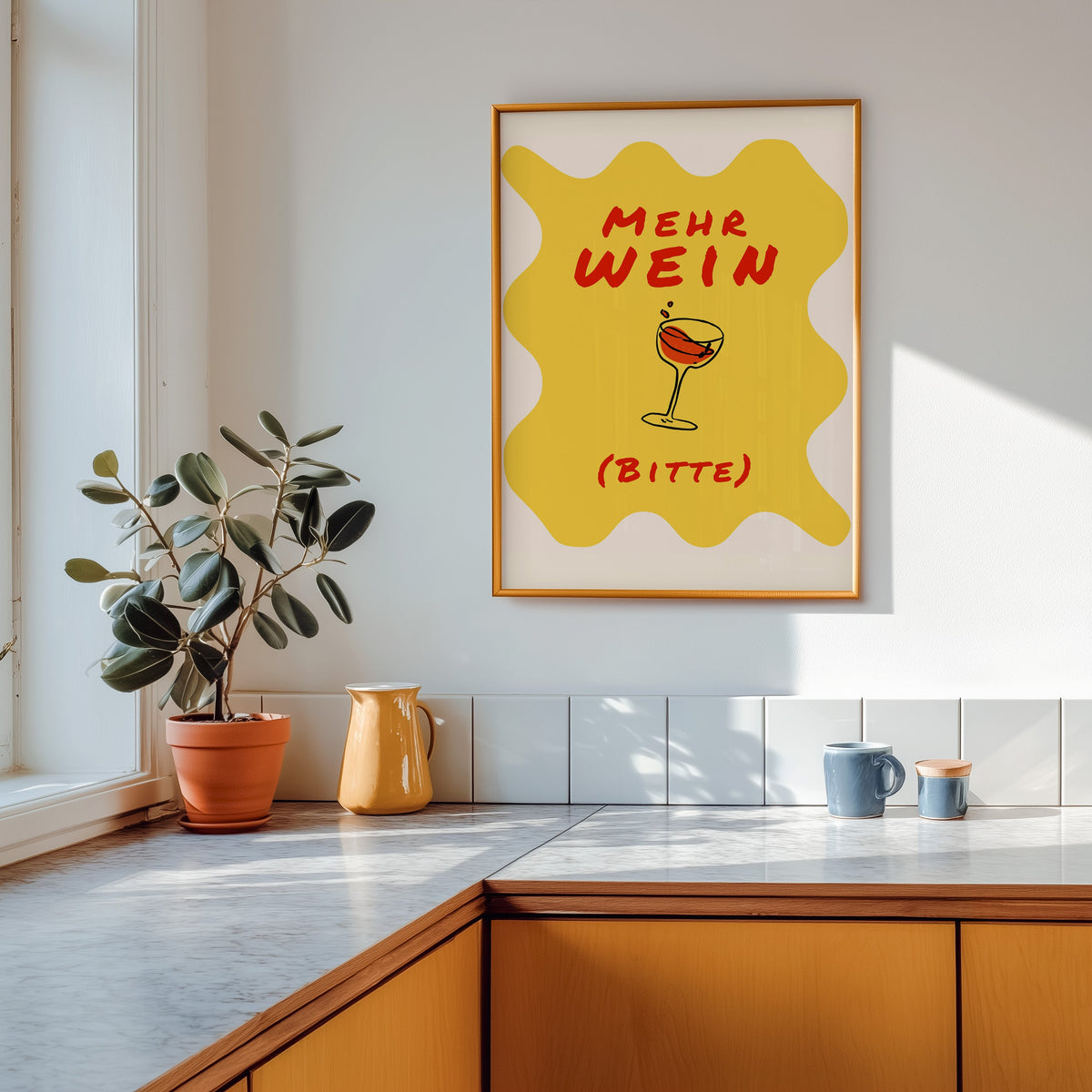 Mehr Wein Bitte print shown in a gold frame above a marble counter in a tan kitchen