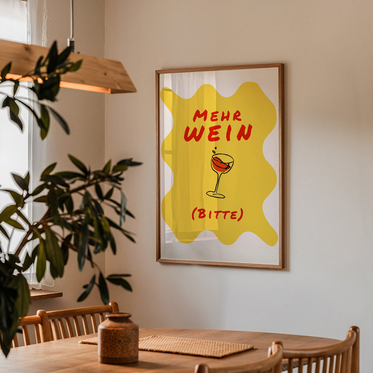 Mehr Wein Bitte print in a walnut frame above a dining table with olive branches