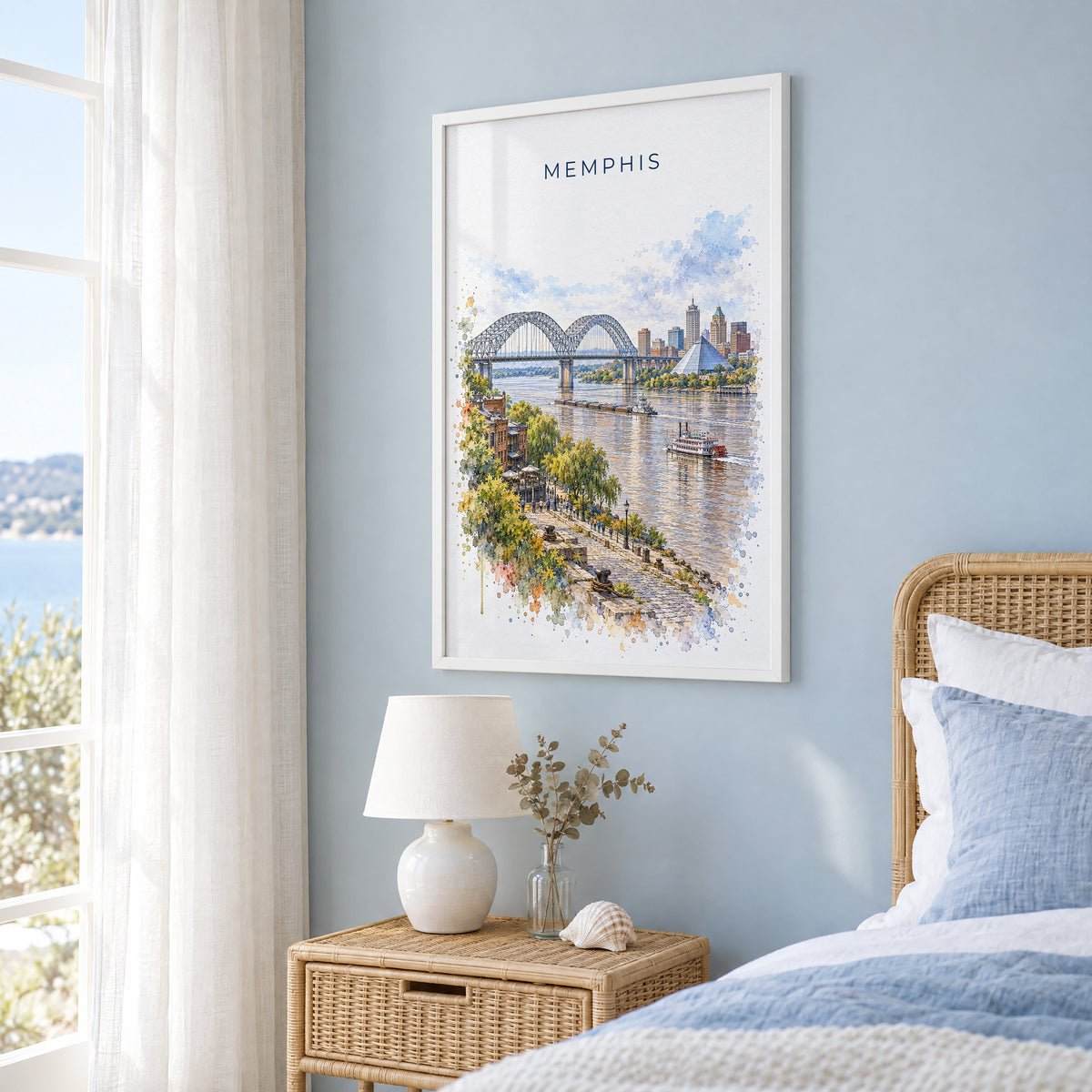 Memphis watercolor print in a white frame on a pale blue wall beside a rattan bed in a coastal bedroom