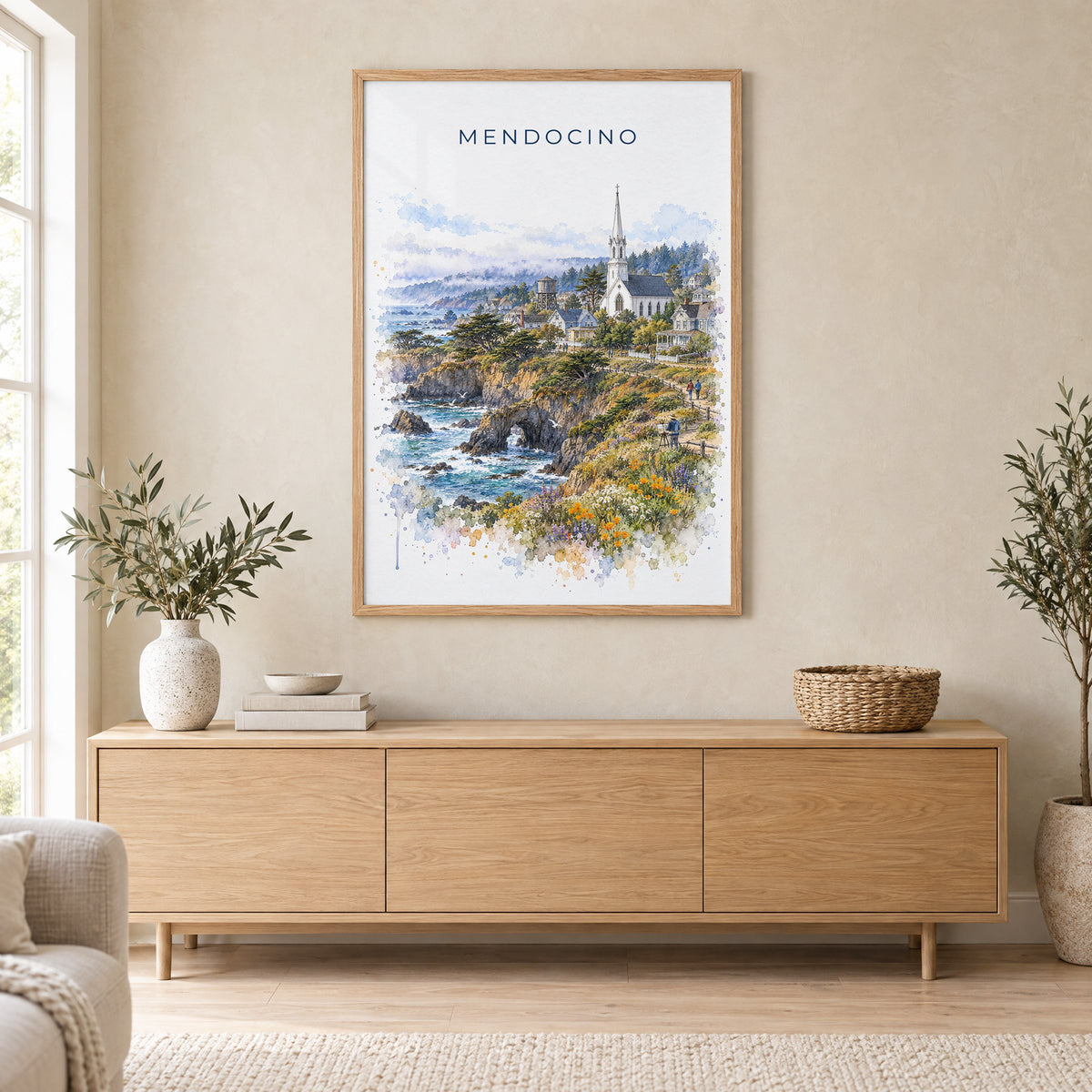 Mendocino watercolor print in an oak frame above a light wood sideboard in a Scandinavian living room
