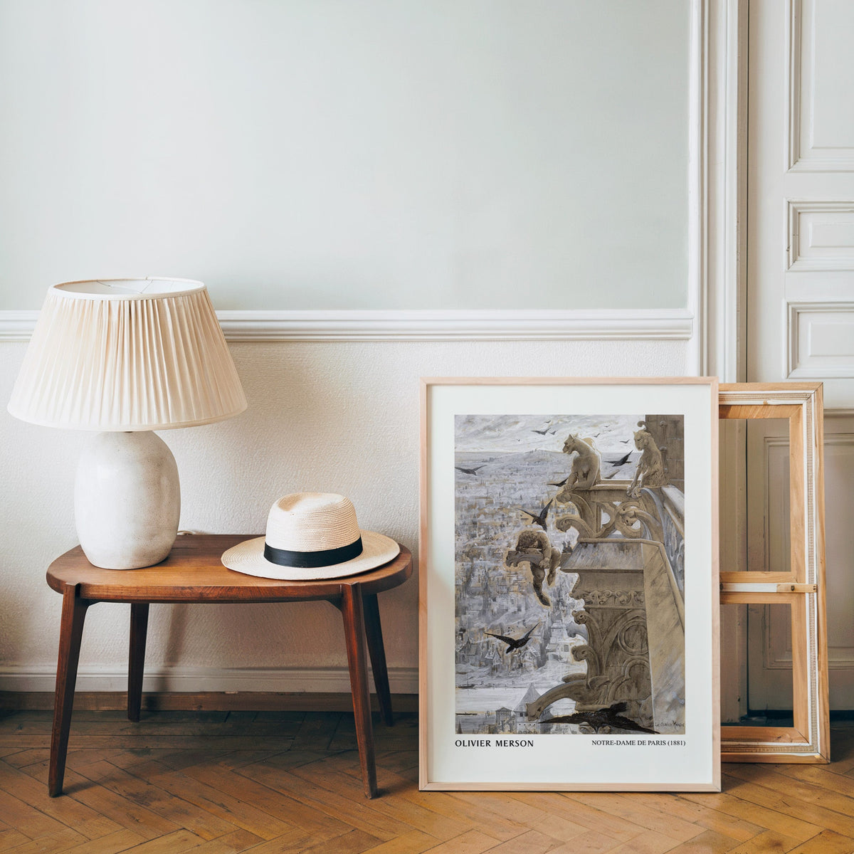 Paris rooftops poster in a light wood frame leaning by a bench and panama hat