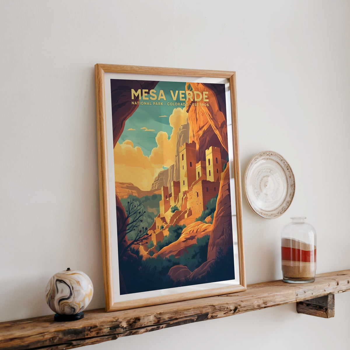 Mesa Verde National Park print in an oak frame on a rustic wood shelf with ceramics and a sand-filled jar