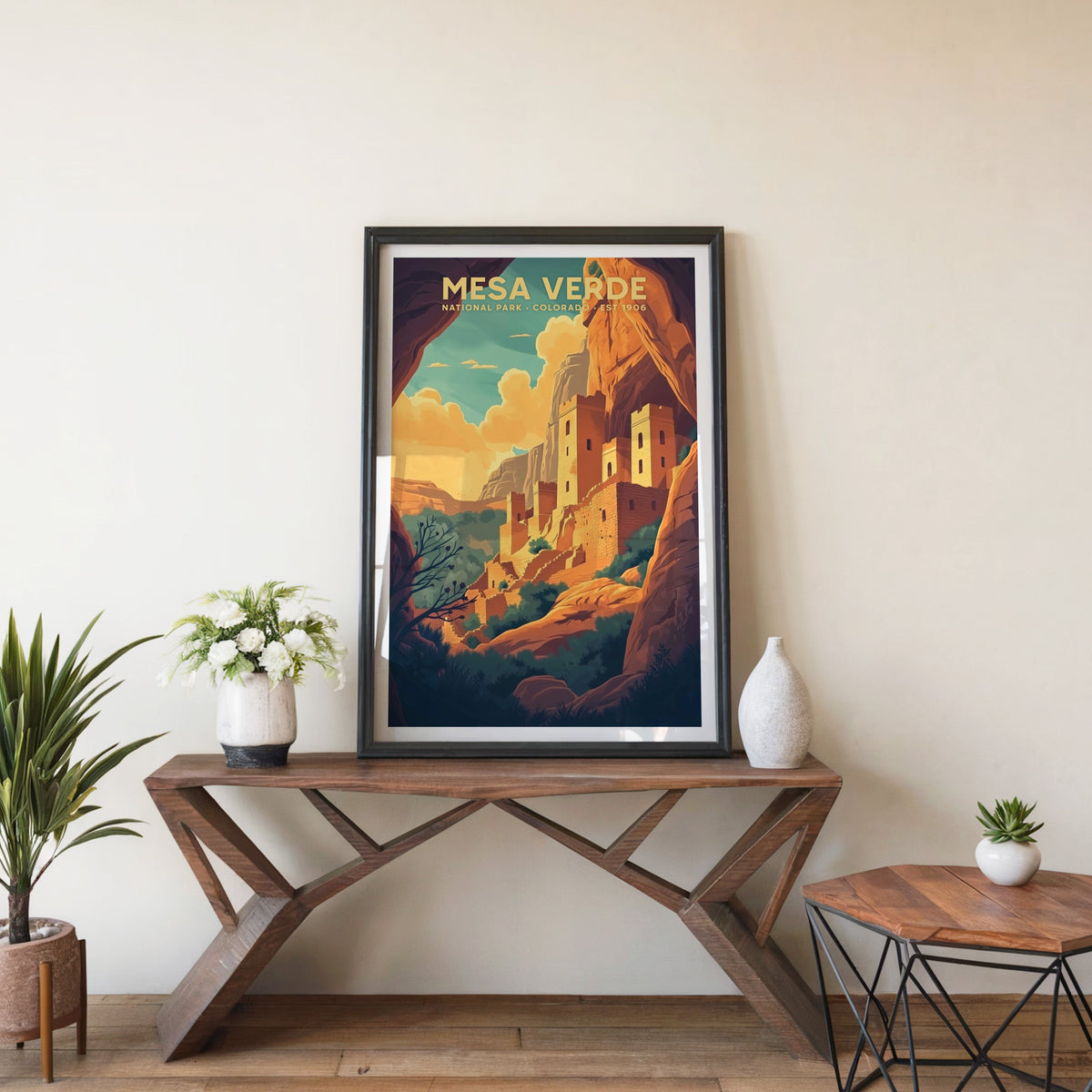 Mesa Verde poster in a black frame on an entryway console table beside white flowers and a yucca
