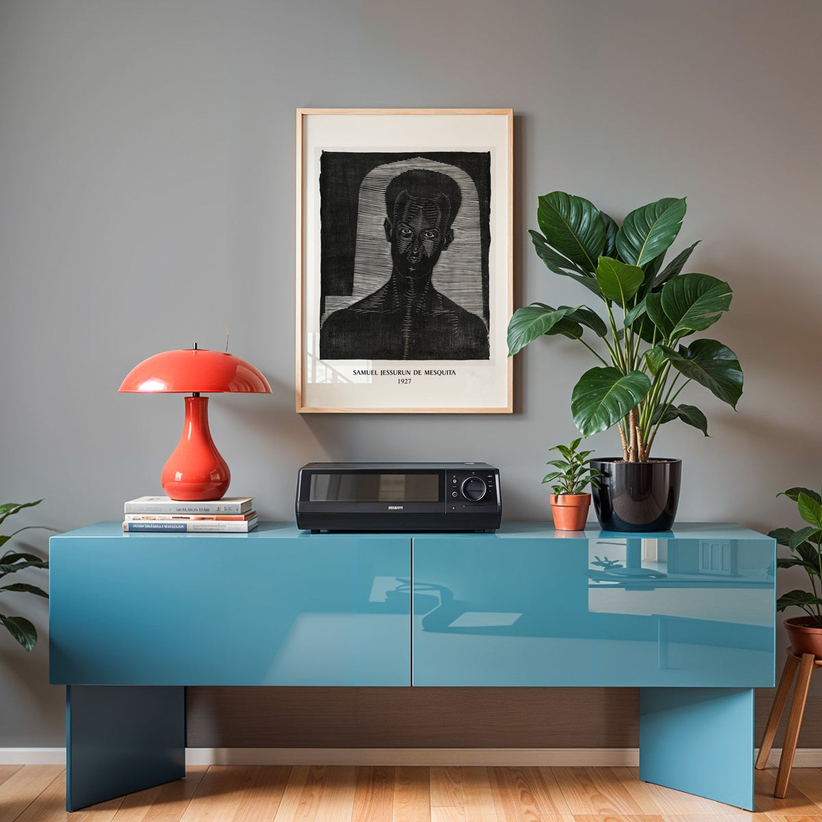 Woodcut face print in an oak frame above a teal sideboard with a red lamp