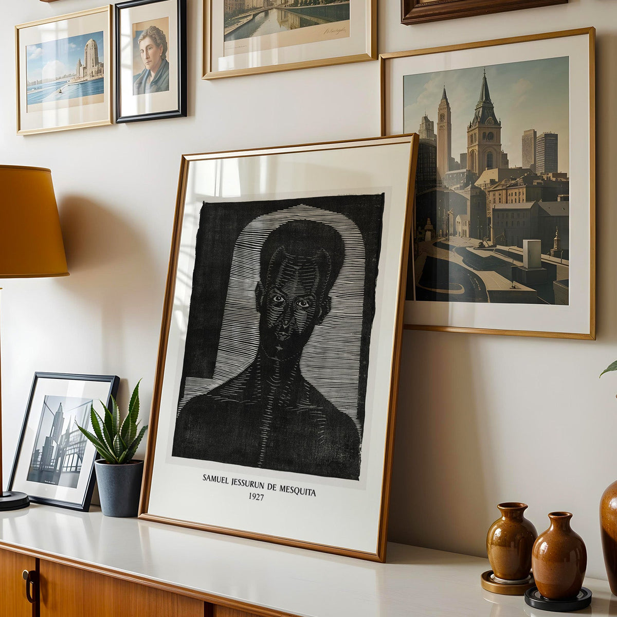 Woodcut print shown in a gold frame leaning on a sideboard in a gallery wall
