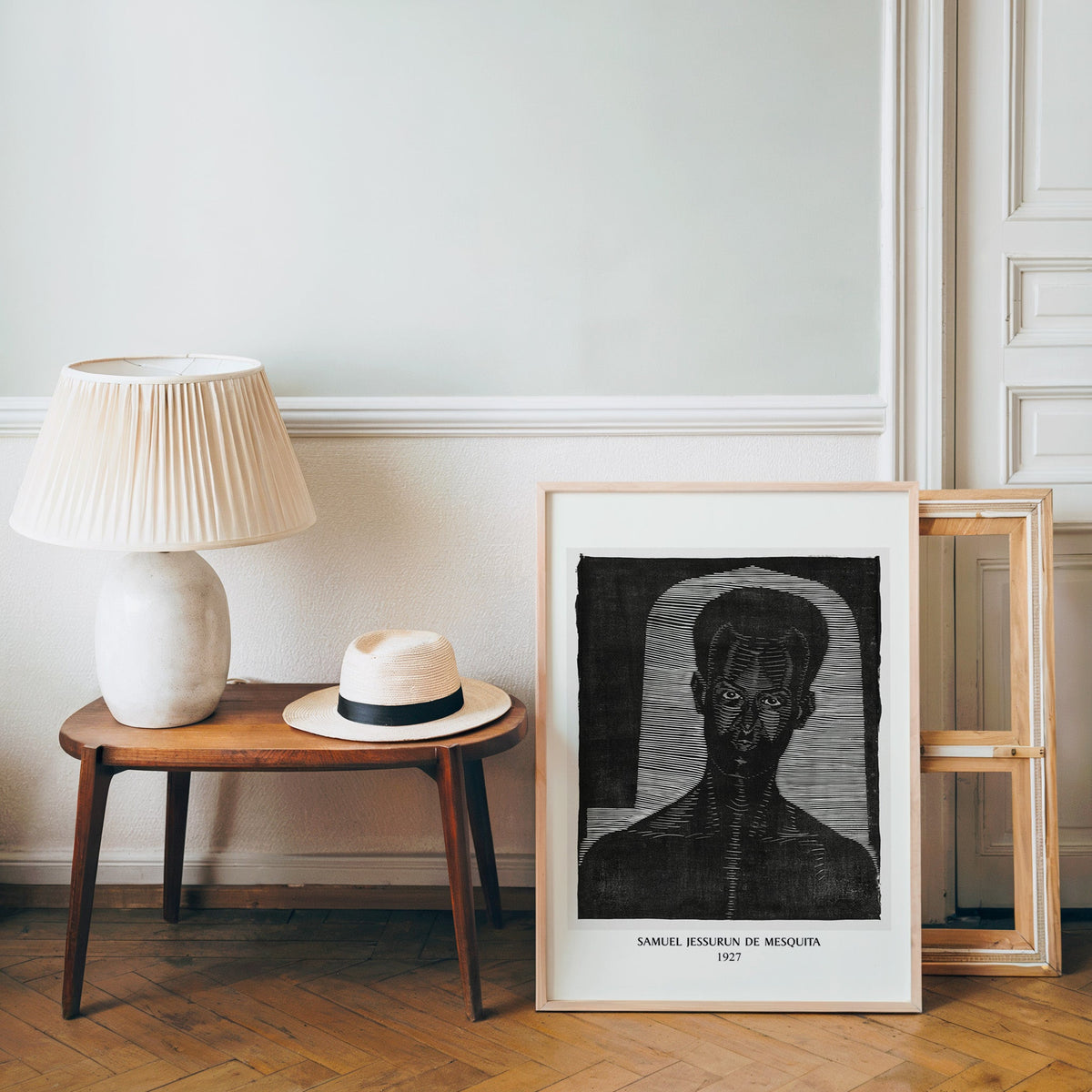 Woodcut portrait poster in a light wood frame leaning by a bench and hat