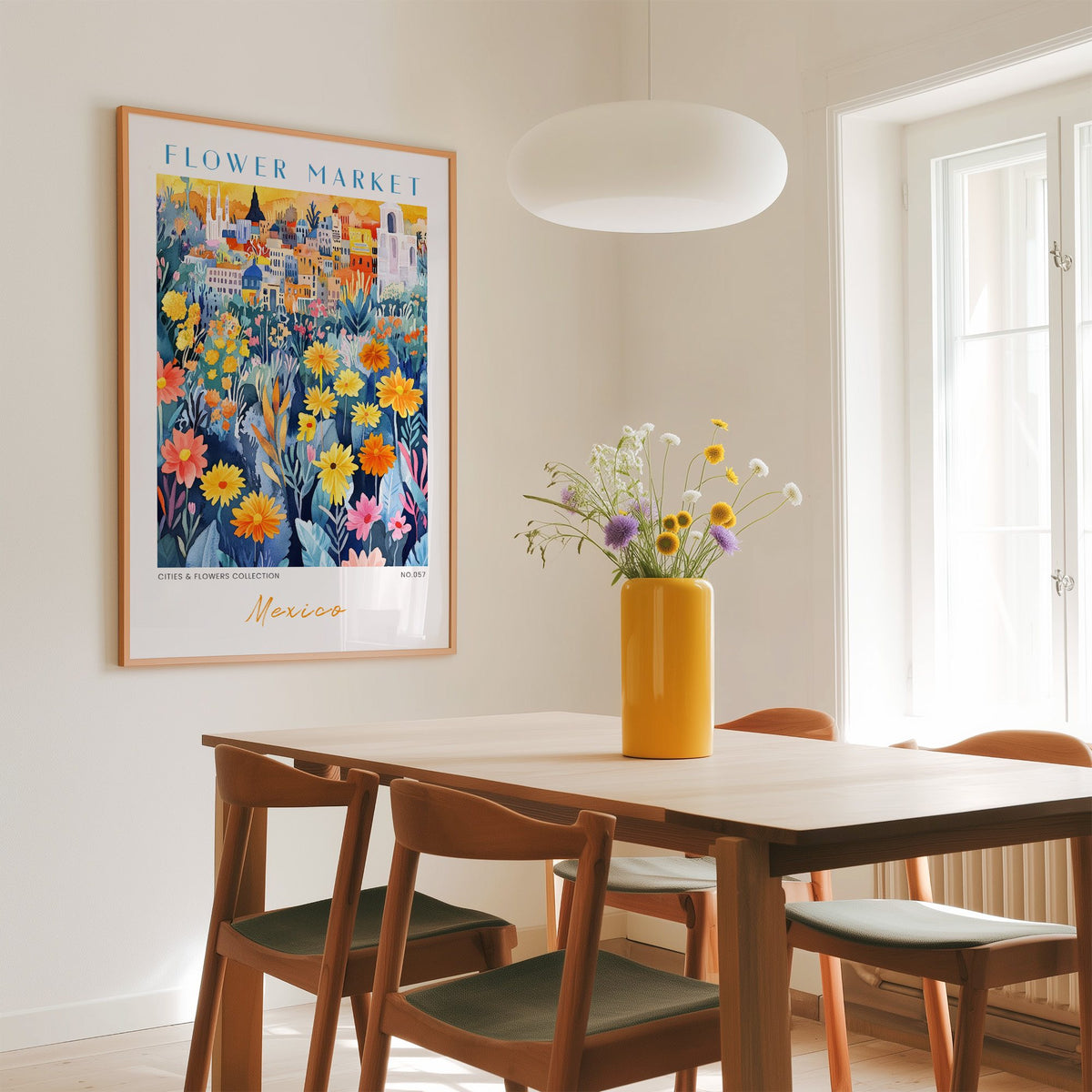 Mexico flower market print in an oak frame above a dining table with a yellow vase and white pendant light