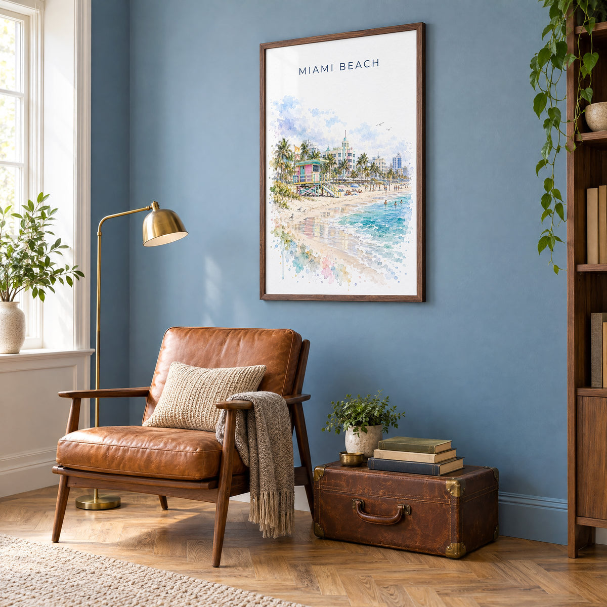Miami Beach watercolor print in a walnut frame on a blue wall above a leather armchair in a reading nook