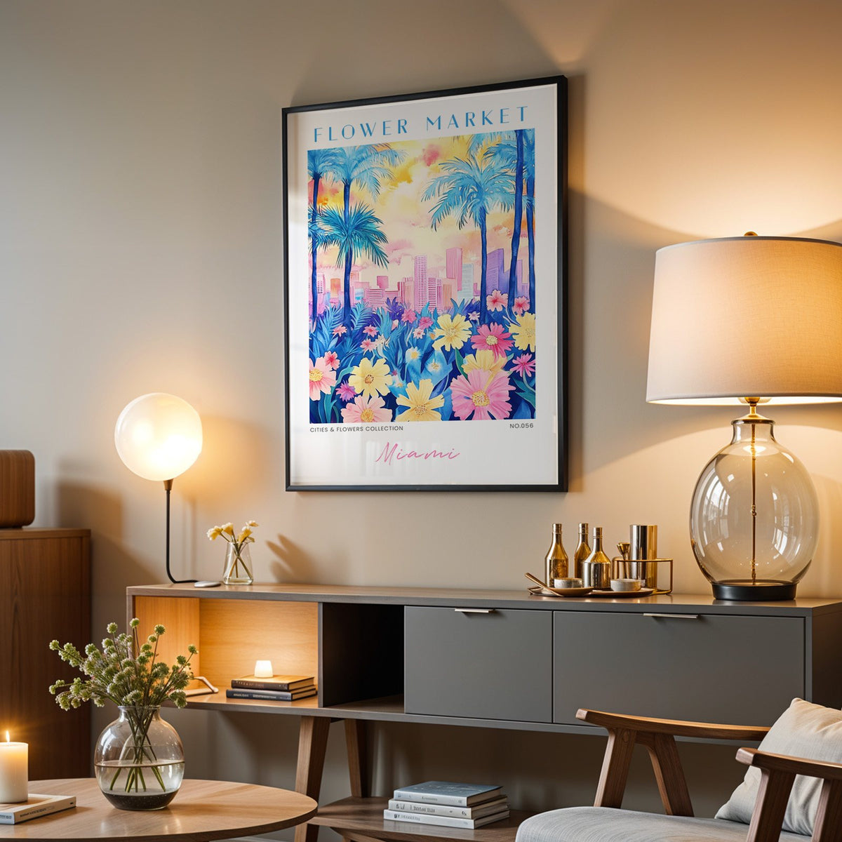Miami flower market print in a black frame above a grey media console with a glass table lamp