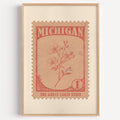 Michigan state flower stamp print in terracotta on peach, light oak frame on a plain white wall
