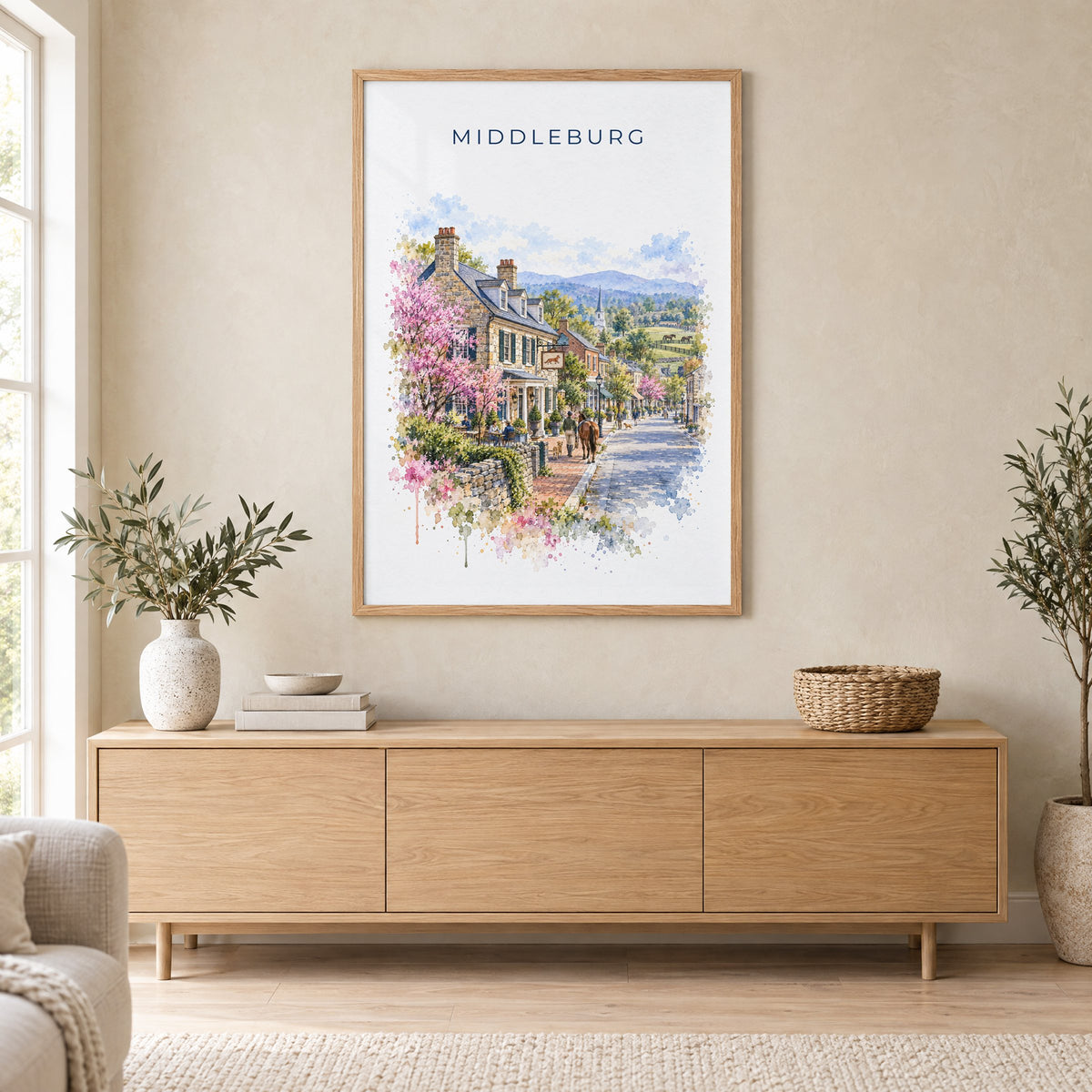 Middleburg, Virginia watercolor print in an oak frame above a light wood sideboard in a Scandinavian living room