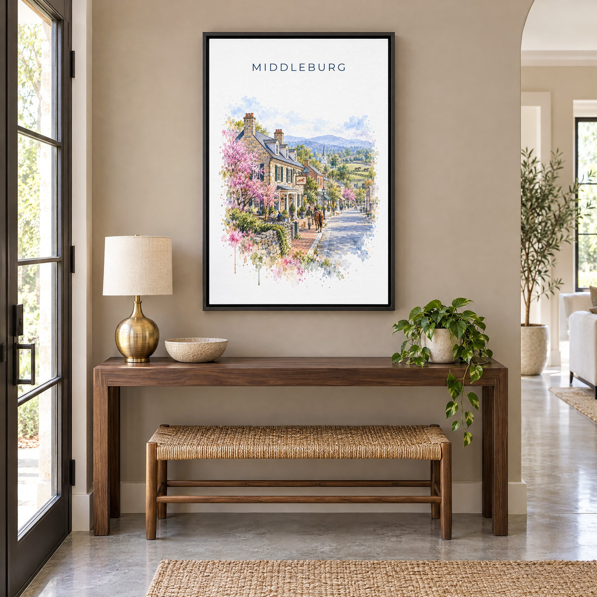 Middleburg, Virginia watercolor print as a black floater canvas above a walnut console and woven bench in an entryway