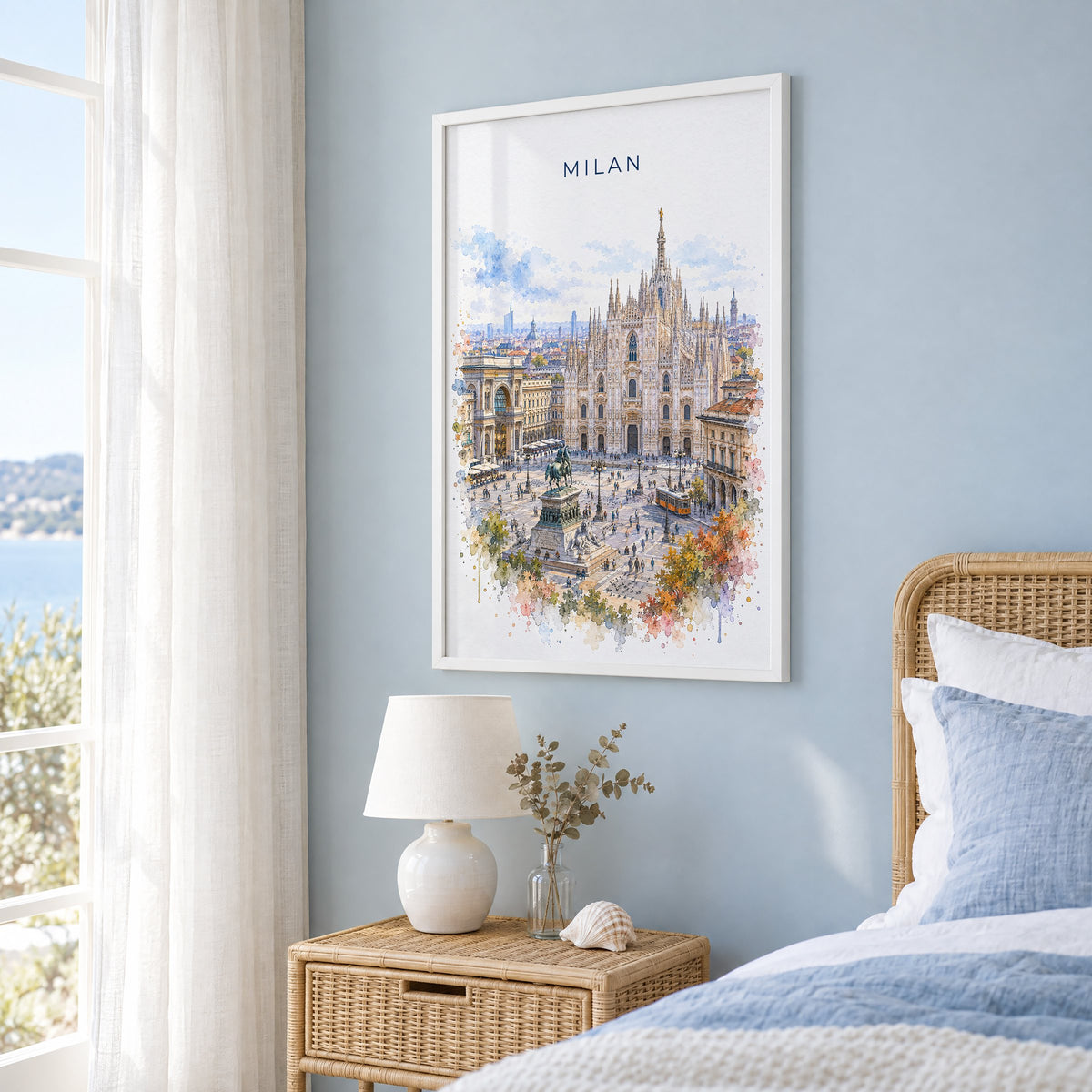 Milan watercolor print in a white frame on a pale blue wall beside a rattan bed in a coastal bedroom
