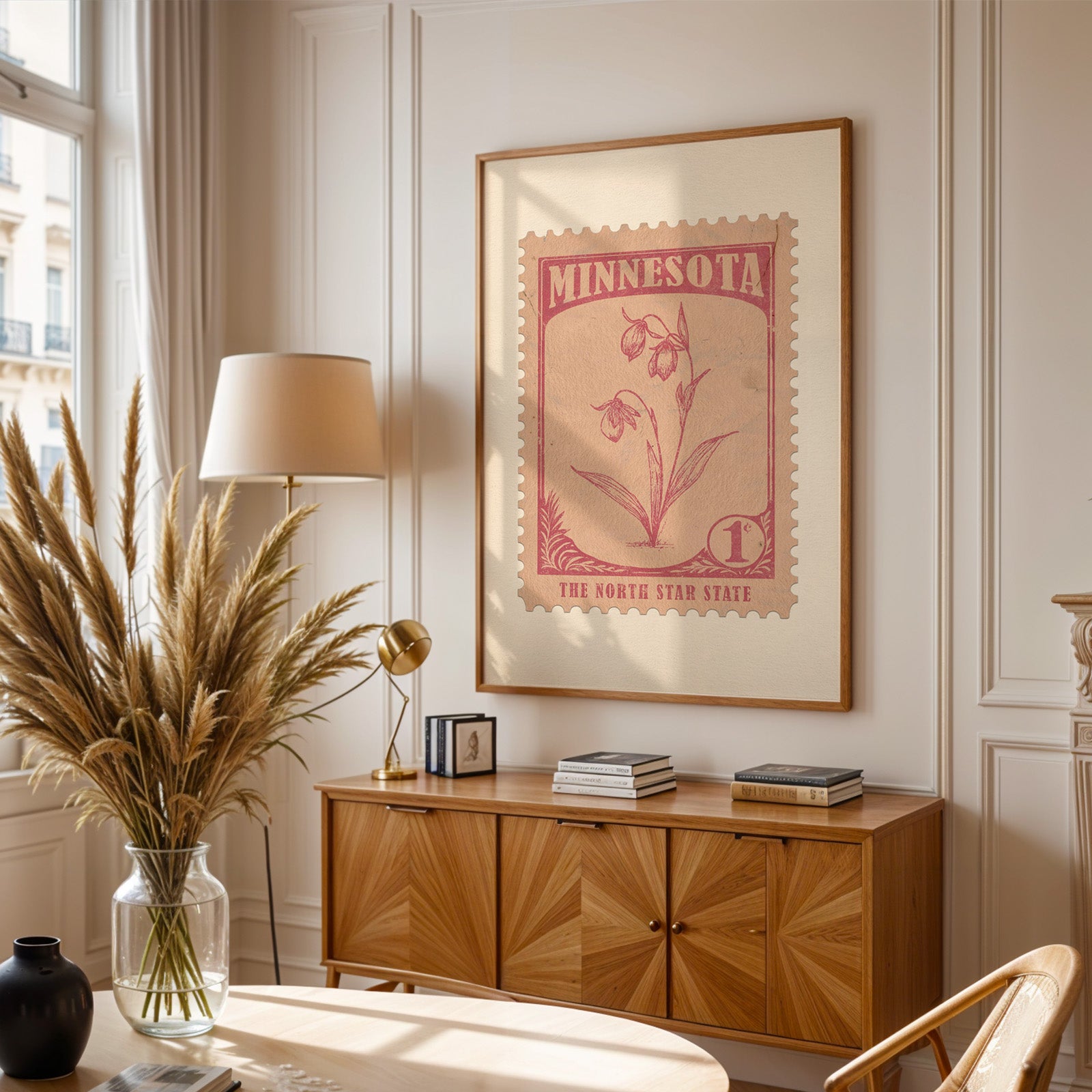 Minnesota stamp print framed above a wooden sideboard, pampas grass in a glass vase and a floor lamp