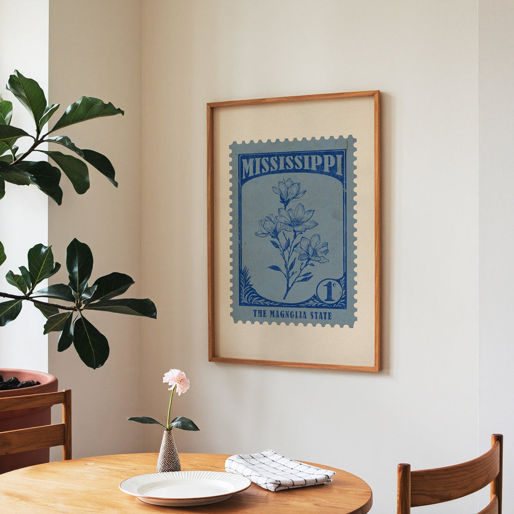 Mississippi state flower print framed above a round wooden table with a single bloom in a vase and books