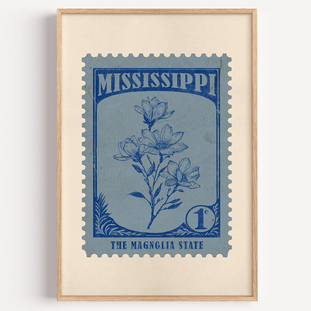 Mississippi state flower stamp print in ink blue on slate, light oak frame on a plain white wall