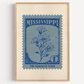 Mississippi state flower stamp print in ink blue on slate, light oak frame on a plain white wall