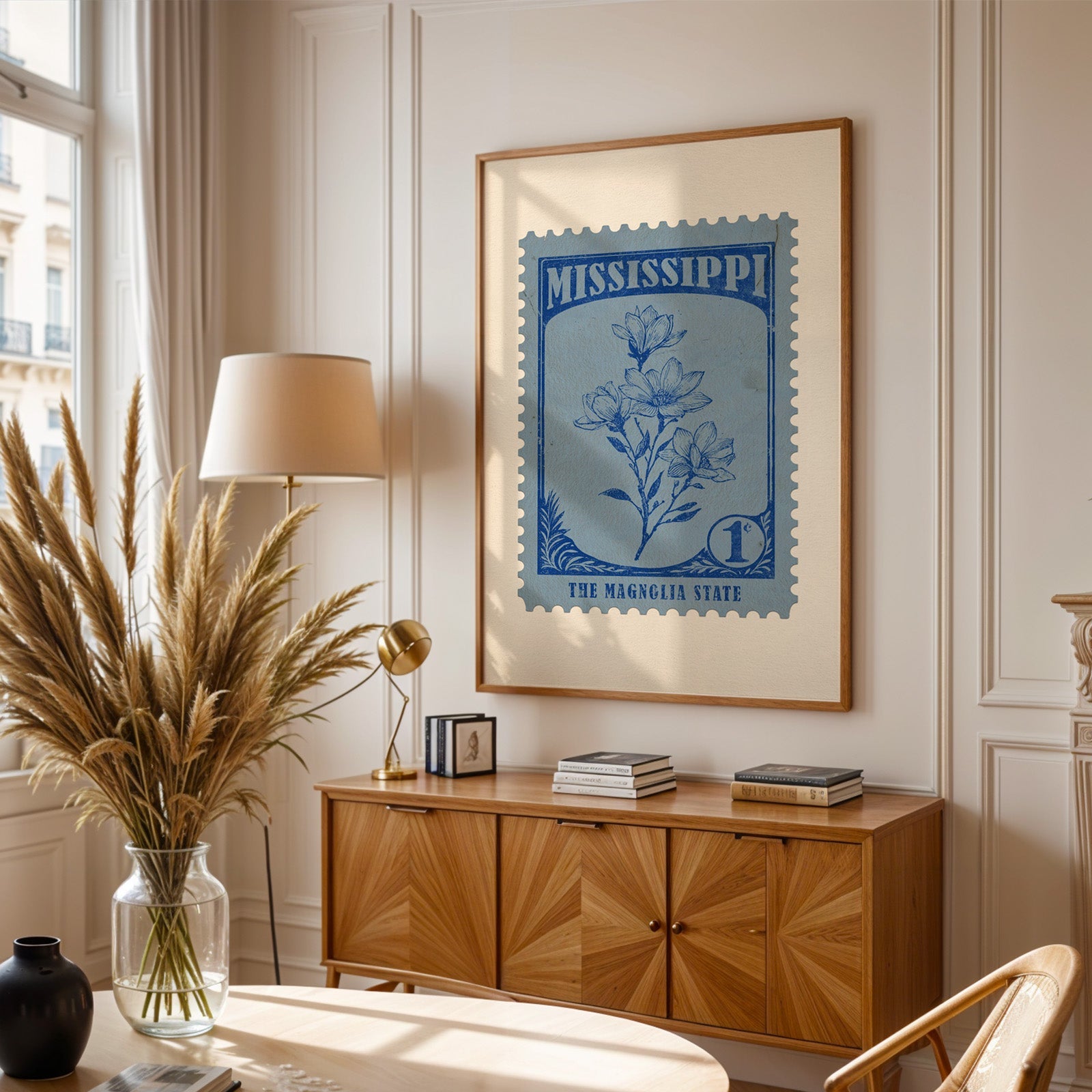 Mississippi stamp print framed above a wooden sideboard, pampas grass in a glass vase and a floor lamp
