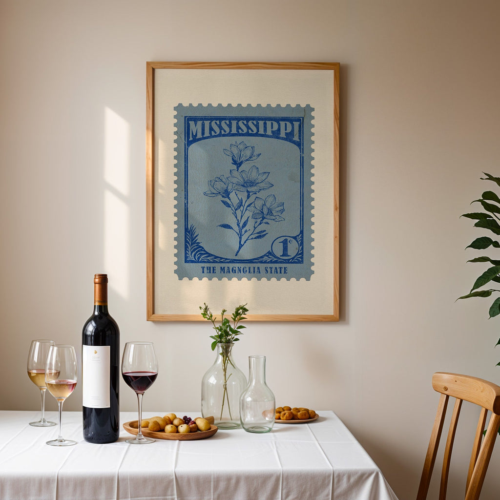 Mississippi stamp print framed on the wall above a dining table set with wine, glasses and olives