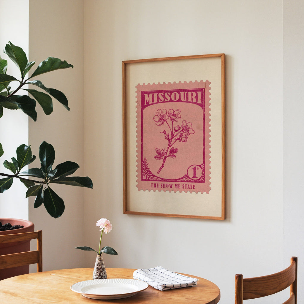 Missouri state flower print framed above a round wooden table with a single bloom in a vase and books