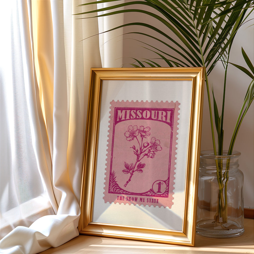 Missouri stamp print in a gold frame leaning by a cream curtain with a palm in a glass jar
