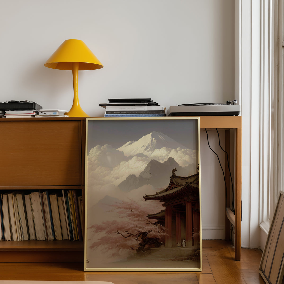 Misty sepia Mount Fuji temple print shown in a gold frame below a teak desk with a yellow lamp