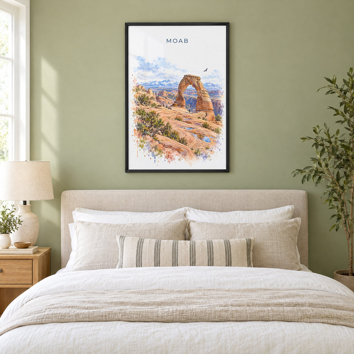 Moab watercolor print in a black frame above an upholstered headboard in a sage green bedroom