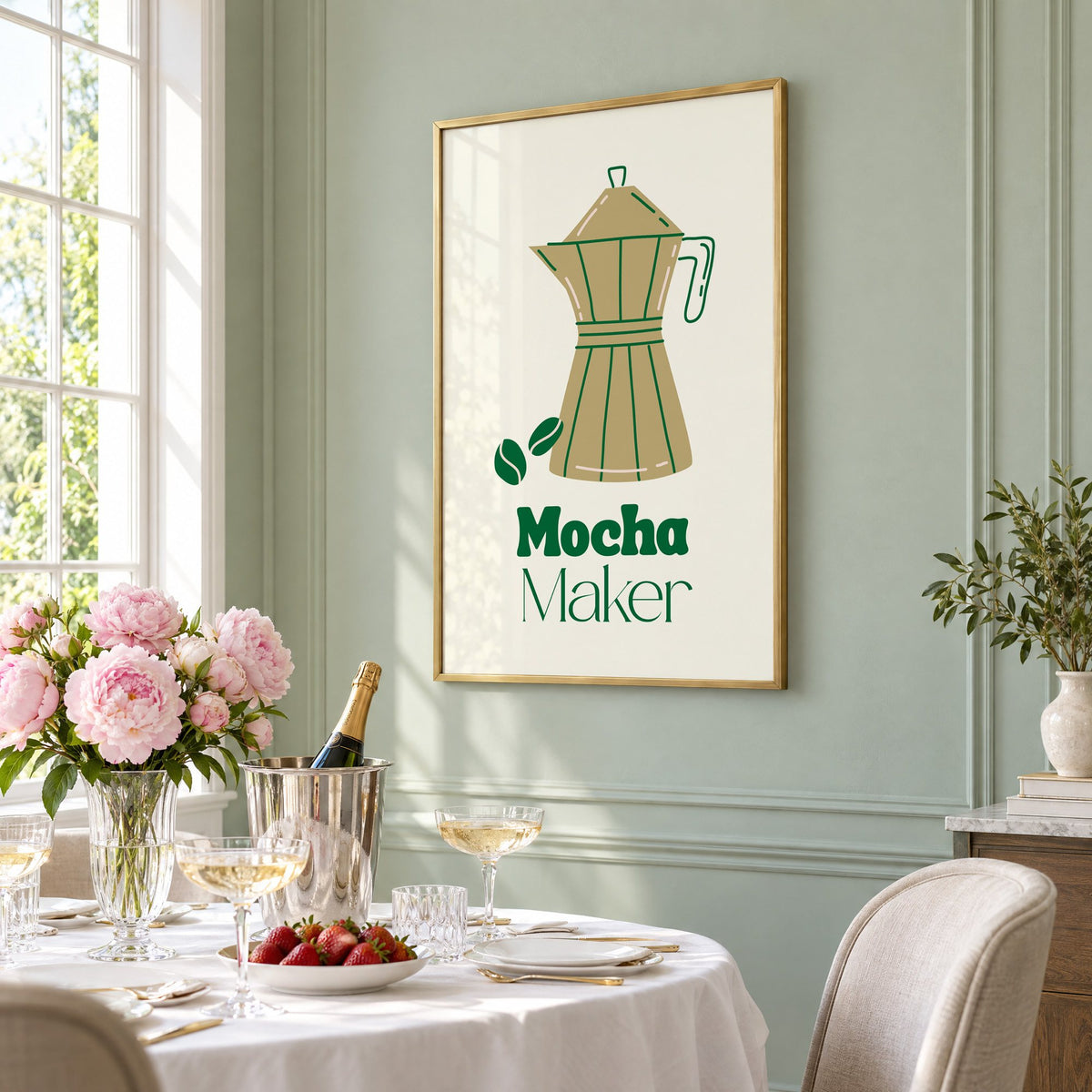 Mocha Maker gold moka pot and beans print in a brass frame on a sage wall above a brunch table with champagne and peonies, seen at an angle