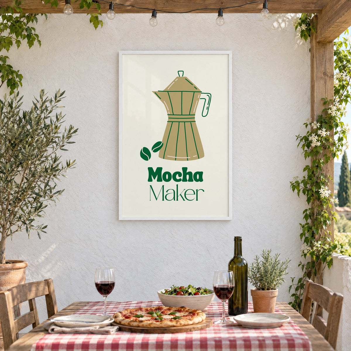 Mocha Maker gold moka pot and beans print in a white frame on a stucco wall above a checked-cloth table with pizza and red wine