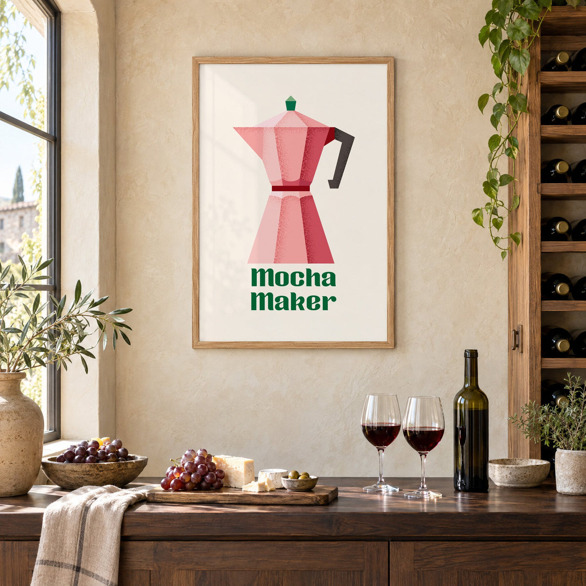 Mocha Maker pink moka pot print in an oak frame on a limewashed wall above a wine counter with red wine, cheese and grapes