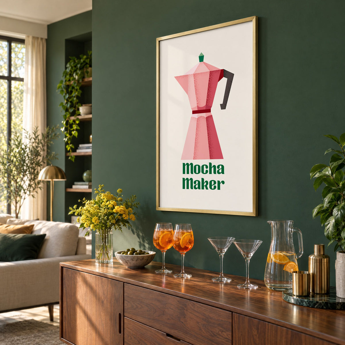 Mocha Maker pink moka pot print in a brass frame on a bottle green wall above a sideboard with spritz and martini glasses, seen at an angle