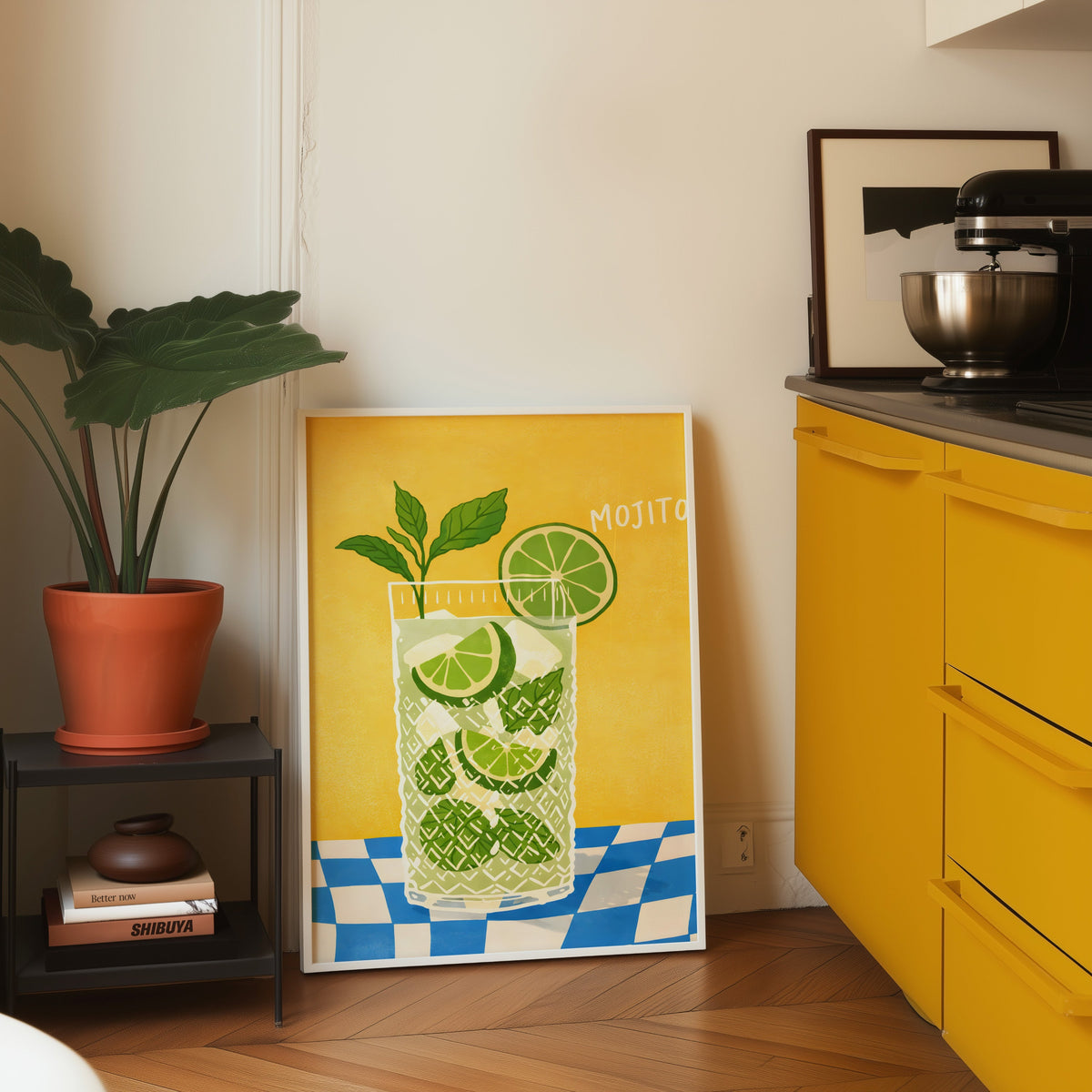 Mojito print in a white frame leaning on parquet beside a bright yellow kitchen