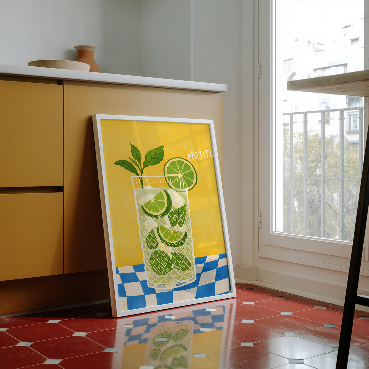 Mojito print in a white frame against yellow cabinets on a red tiled floor