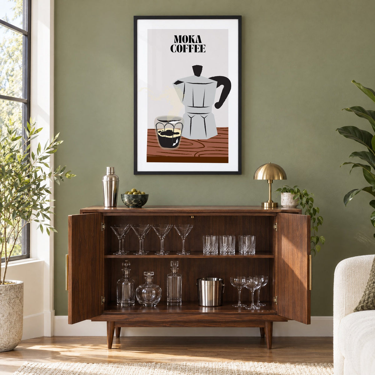 MOKA COFFEE silver pot wood table print in a black frame on an olive green wall above a walnut bar cabinet with glassware