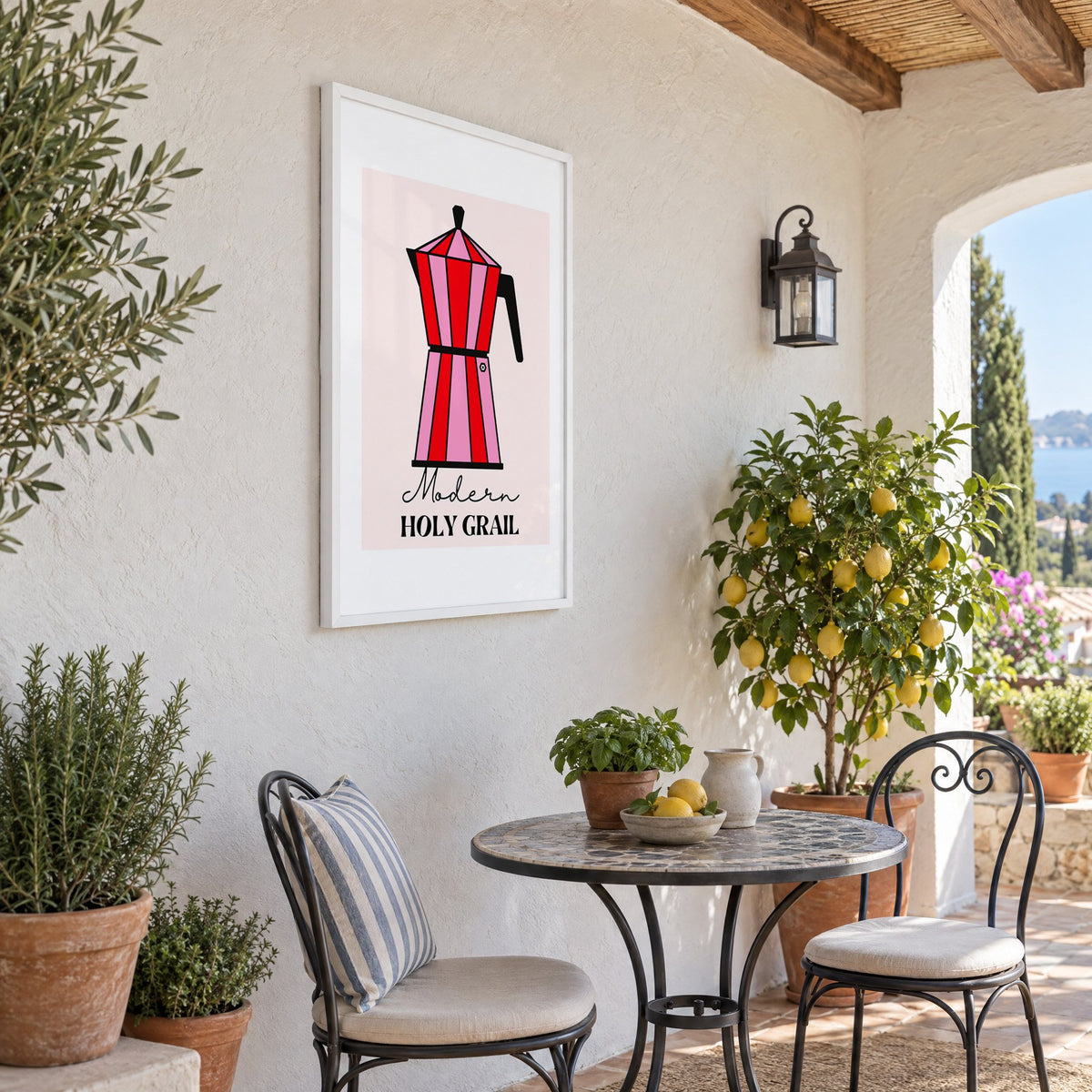 Moka pot pink and red striped print in a white frame on a sunny patio wall beside a potted lemon tree