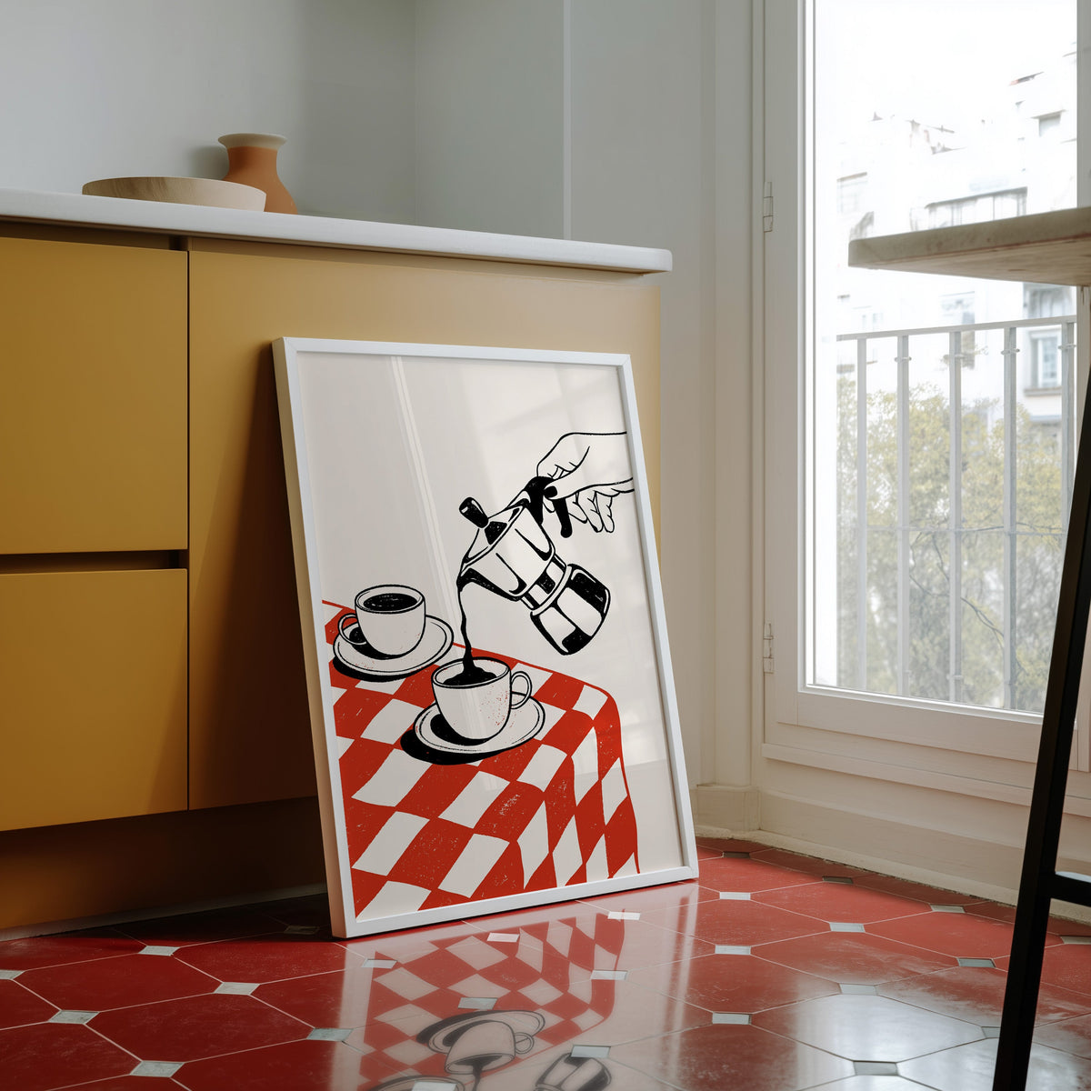 Moka pot print in a white frame against yellow cabinets on a red tiled floor