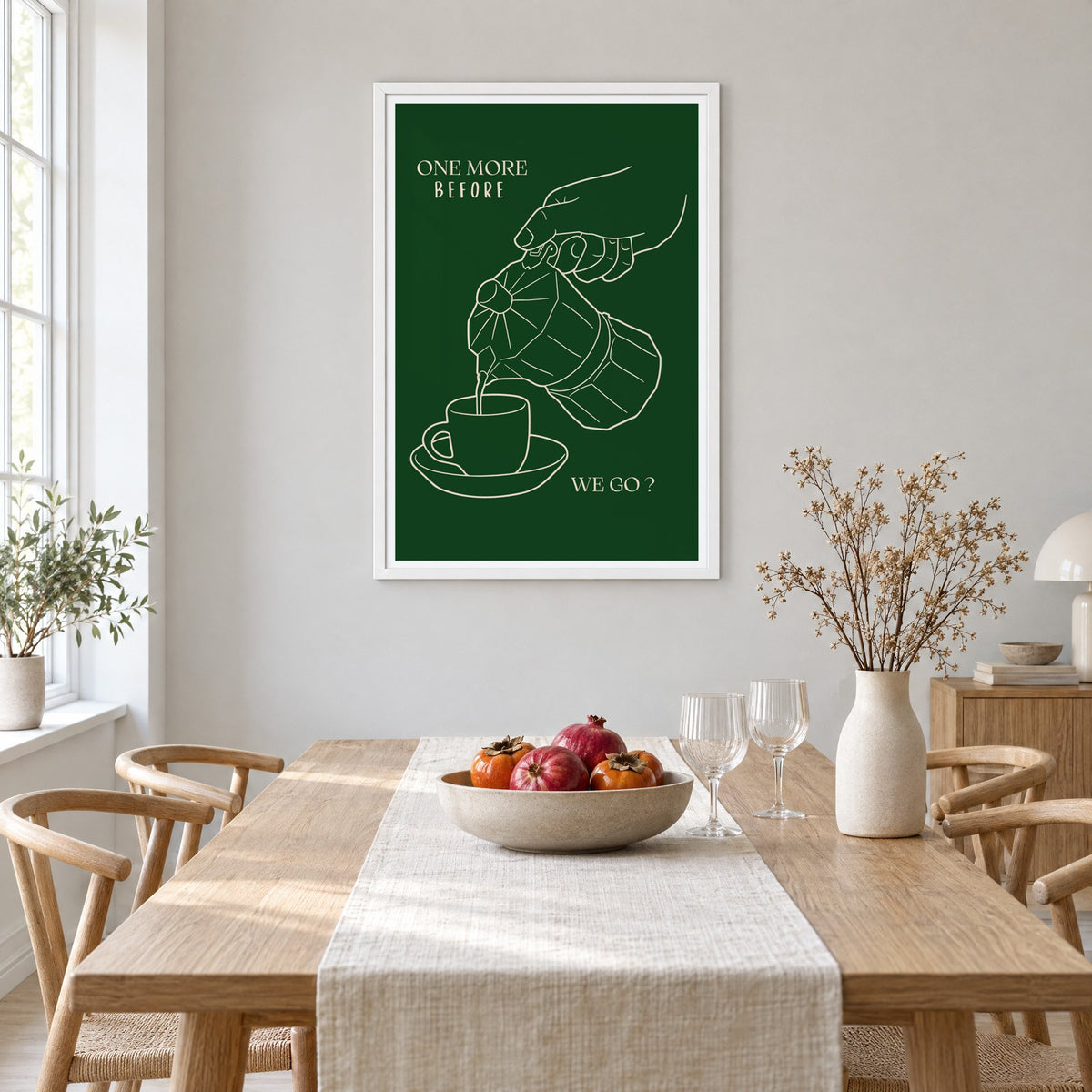 ONE MORE BEFORE WE GO? moka pot line print in a white frame above a light oak dining table with a linen runner and fruit bowl
