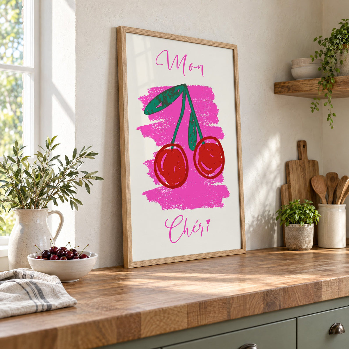Mon Chéri cherries crayon print in an oak frame leaning on a butcher block island beside a bowl of cherries