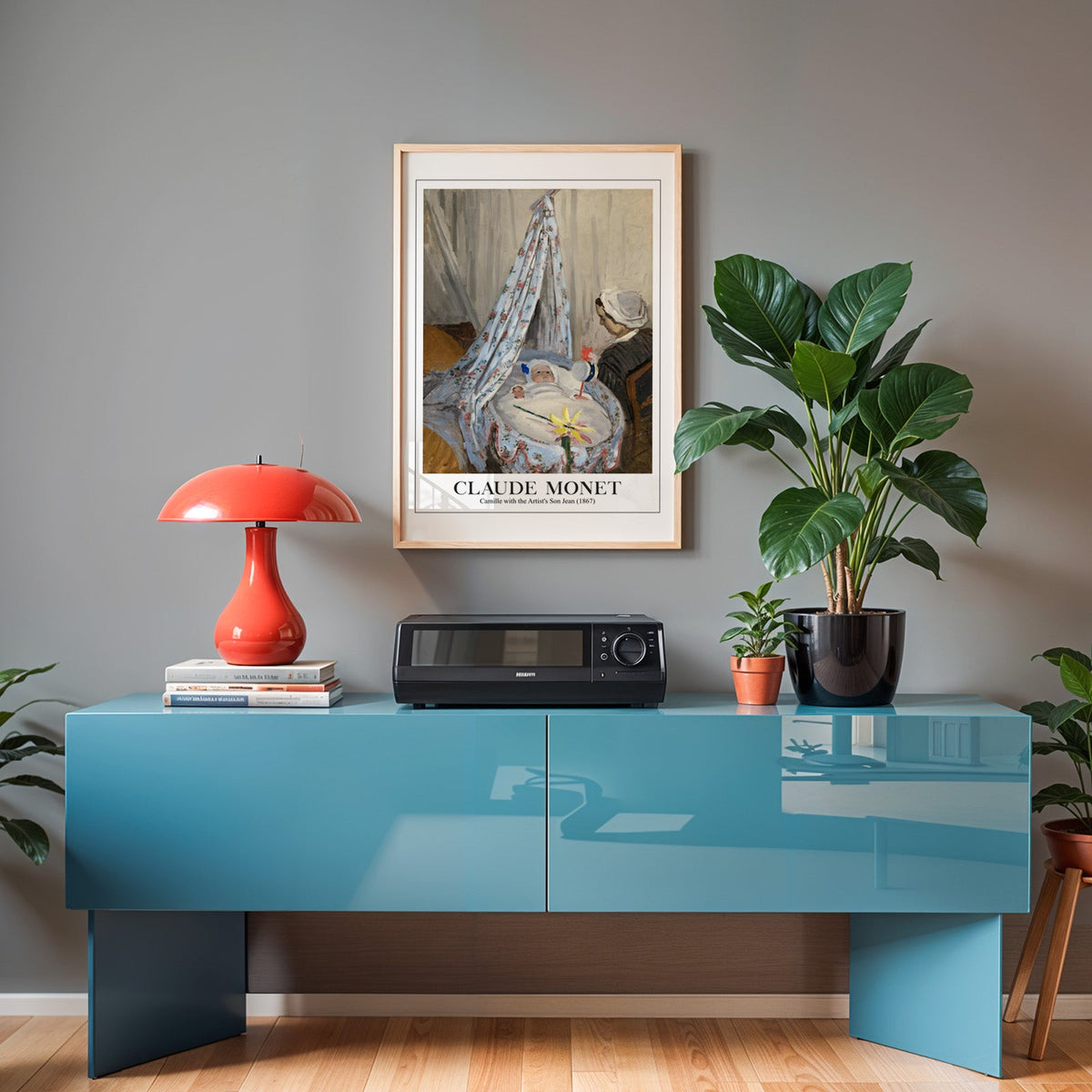 Monet family scene poster in an oak frame above a teal sideboard with a red lamp