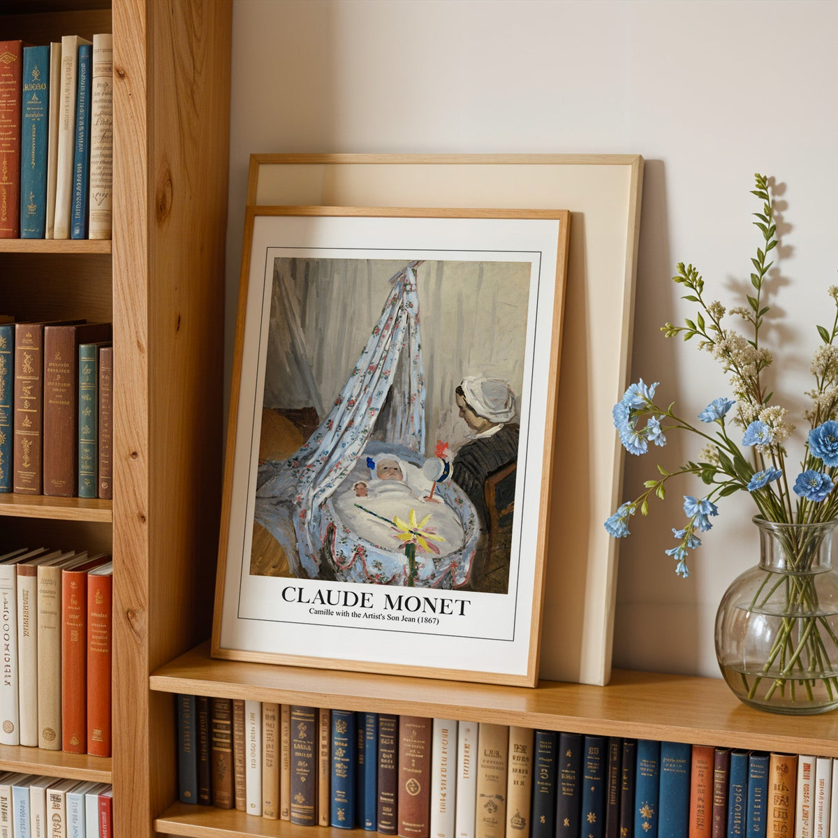 Monet cradle print in an oak frame leaning on a bookshelf beside blue flowers