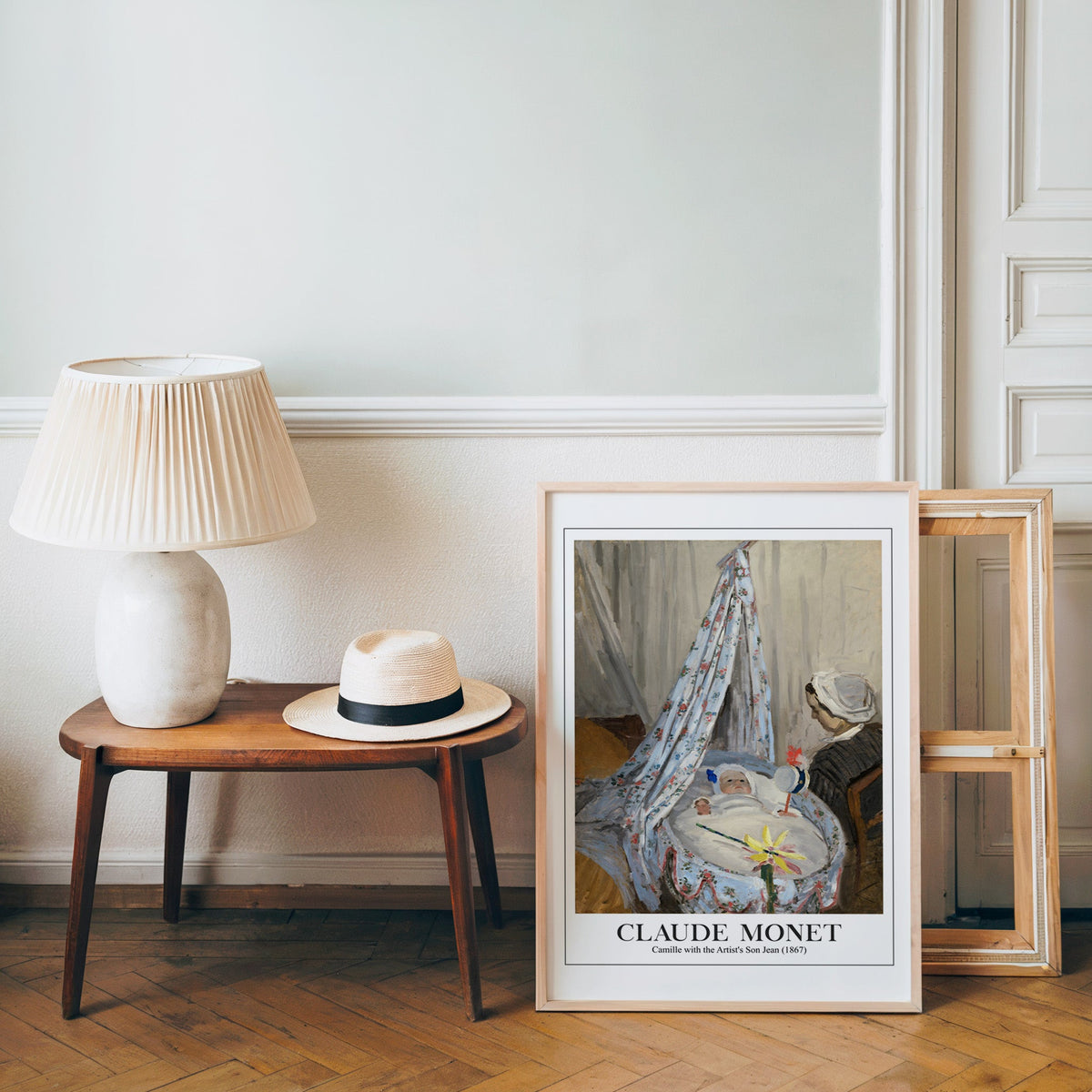 Monet nursery-friendly print in a light wood frame leaning by a bench and hat