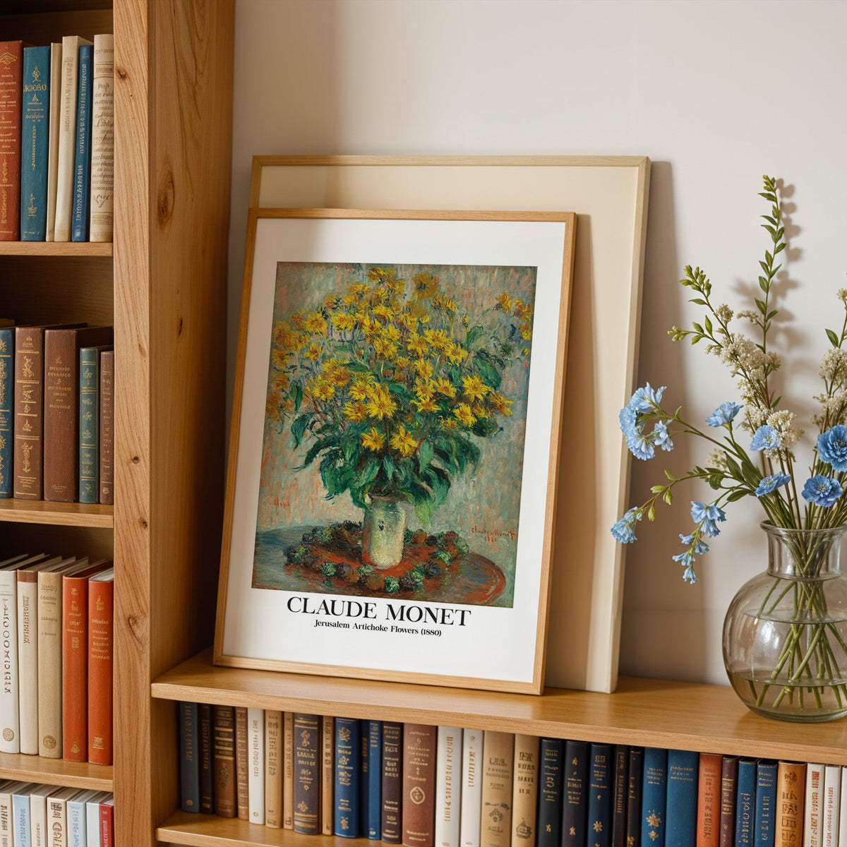 Monet yellow bouquet print in an oak frame leaning on a bookshelf beside blue flowers