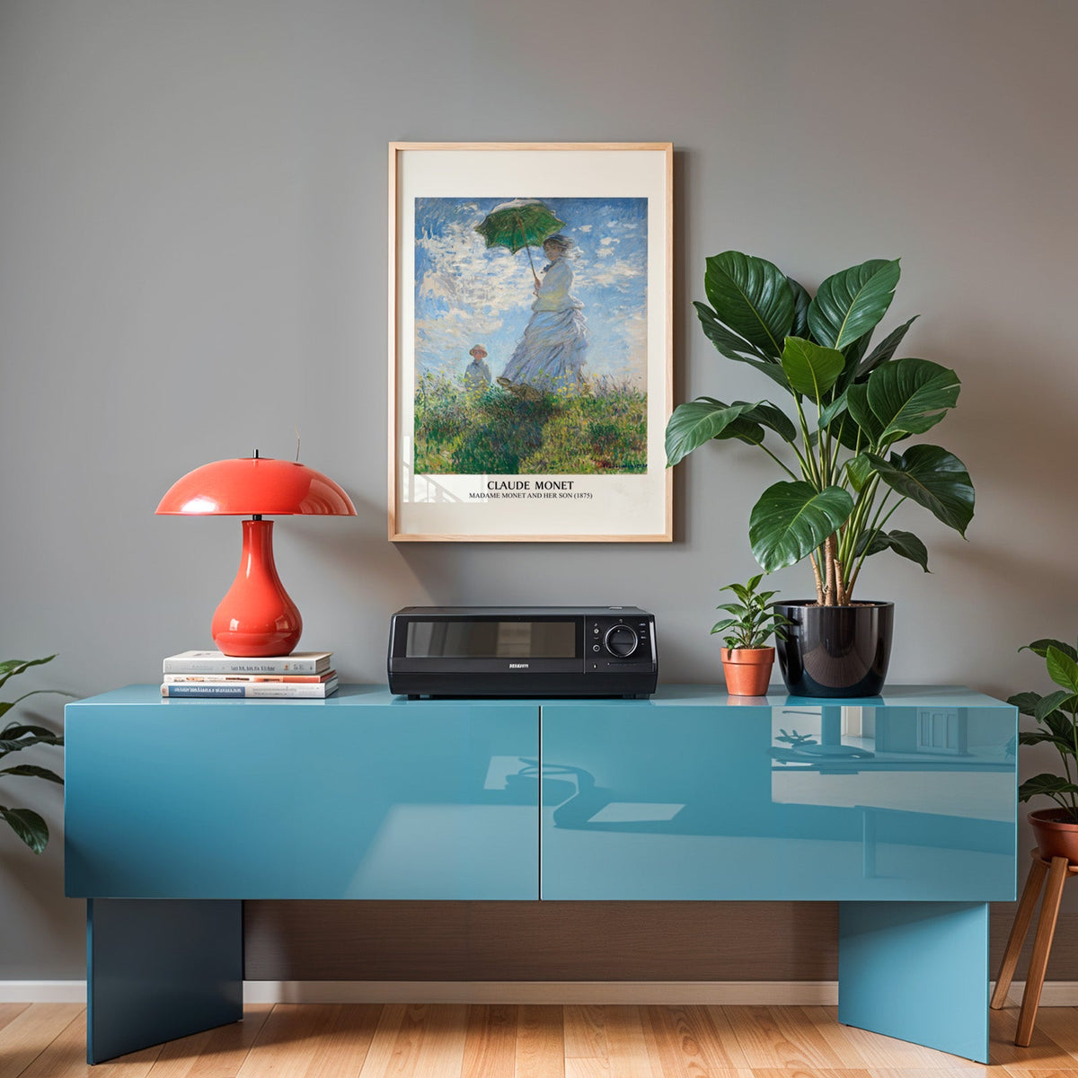 Monet impressionist poster in an oak frame above a teal sideboard with a red lamp
