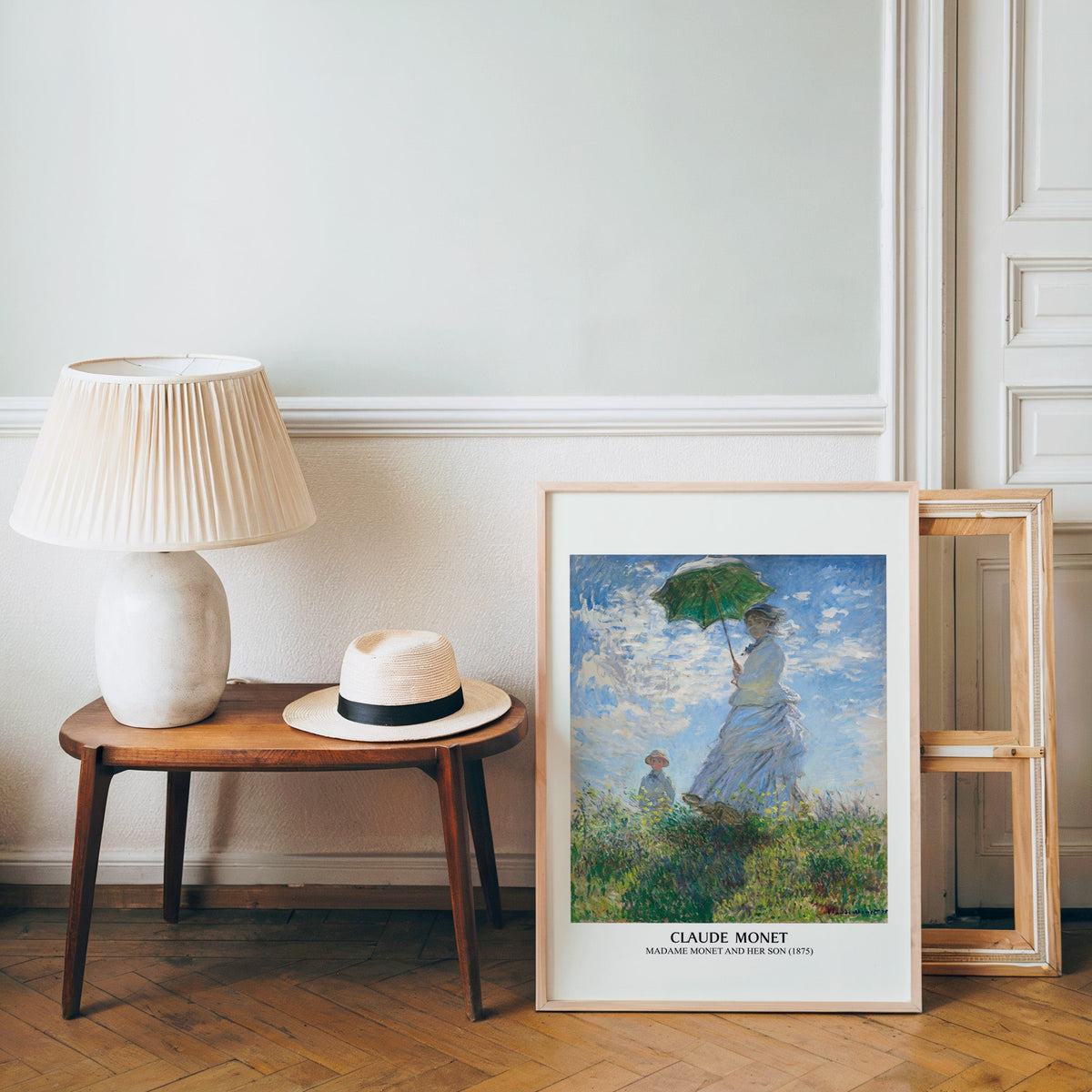Monet impressionist poster in a light wood frame leaning by a bench and panama hat