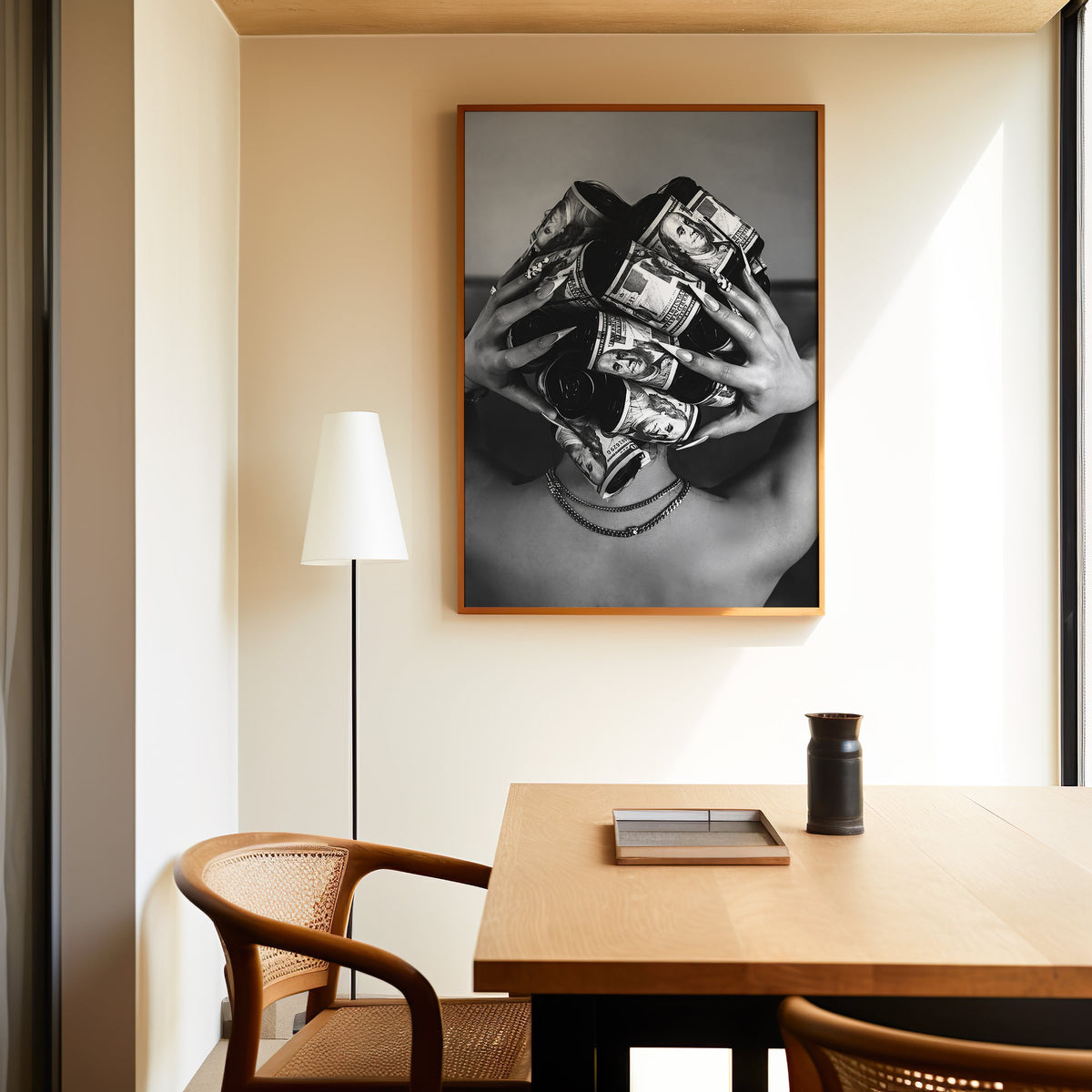 Hair curlers wrapped in dollar bills from behind print in an oak frame above a dining table and cane chair