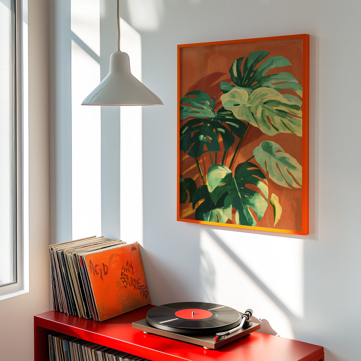 Monstera botanical print shown in an orange frame above a red record cabinet and turntable