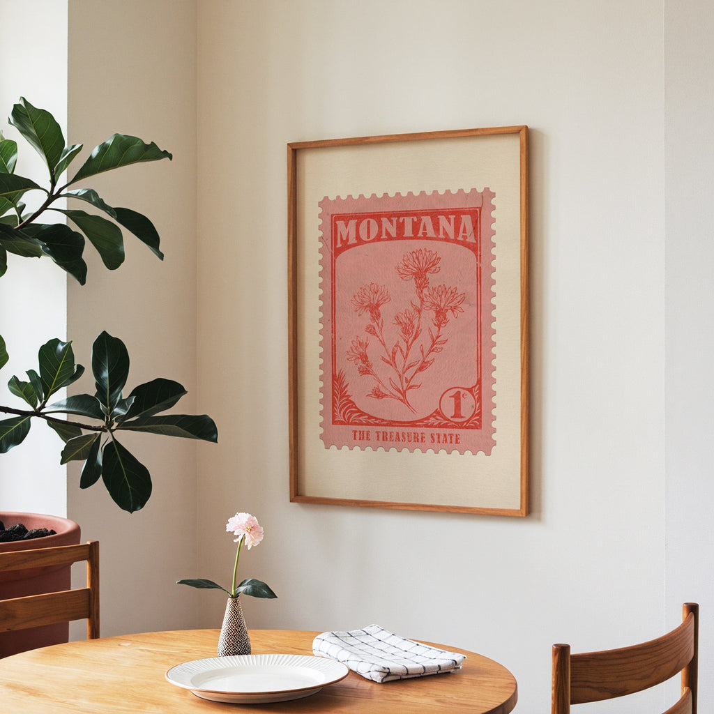 Montana state flower print framed above a round wooden table with a single bloom in a vase and books