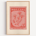 Montana state flower stamp print in vermilion on warm pink, light oak frame on a plain white wall